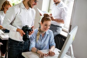 Close up of creative startup young business people with digital camera working together at designer agency in office